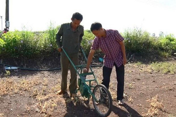 Anh Nguyễn Văn Anh (phải) hướng dẫn người dân sử dụng máy gieo hạt và bón phân.